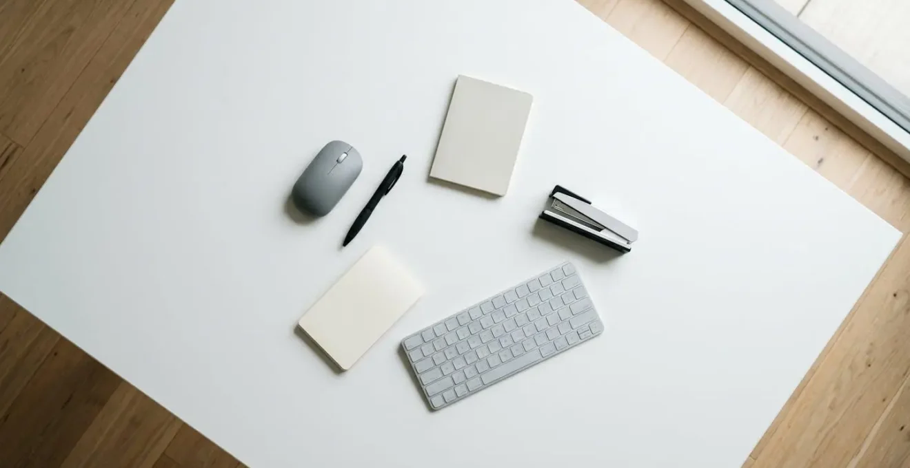 Vue aérienne d'un bureau de travail minimaliste avec cinq objets essentiels disposés en cercle rapproché pour une ergonomie optimale